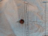 the back of a pair of blue shorts with a button on it