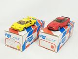 two toy cars sitting on top of boxes on a white surface
