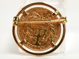 a gold brooch with a coin on it