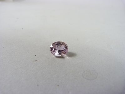 un gros plan d'un diamant rose sur une surface blanche