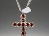 a silver cross with red stones and a ribbon on a gray background