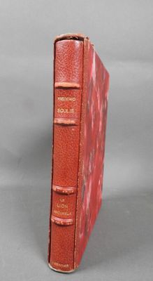 an old red book sitting on top of a gray surface