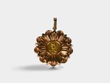 a close up of a gold flower pendant on a white background