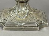 a silver candle holder with a candle on top of it