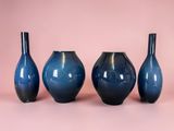 three blue vases sitting next to each other on a pink surface
