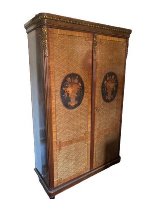 a tall cabinet with two doors and a basket on top of it