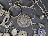 many different types of silver jewelry on a table
