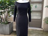 une robe noire posée sur un mannequin devant une porte