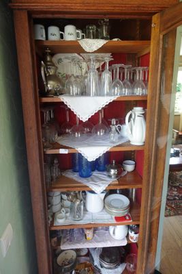 une grande armoire en bois sur laquelle sont disposés de nombreux plats et verres