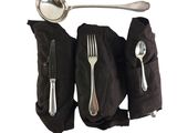 a spoon, fork, and spoon rest on a black napkin