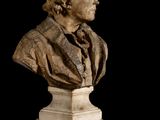 statue of a bust of a man on a pedestal with a black background