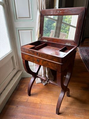 une table en bois sur laquelle est posé un miroir, devant une fenêtre
