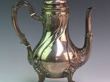 a silver tea pot on a stand on a table