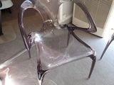 une chaise en plastique transparent posée au milieu d'un salon