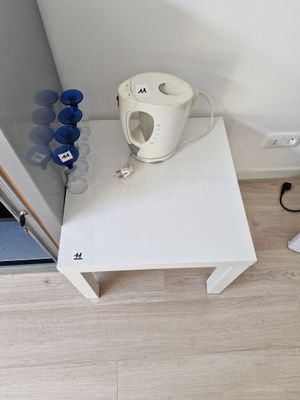 une table blanche sur laquelle se trouve une tasse, près d'une porte
