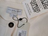 the label on a white sweater is attached to a button