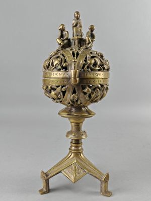 a brass vase on a stand on a white background