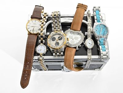 de nombreuses montres et bracelets dans un coffret posé sur une surface blanche