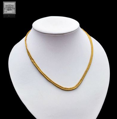a close up of a gold necklace on a mannequin mannequin