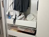 a white closet with clothes and shoes on the shelves
