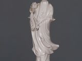 une statue représentant une femme tenant une fleur, posée sur une table