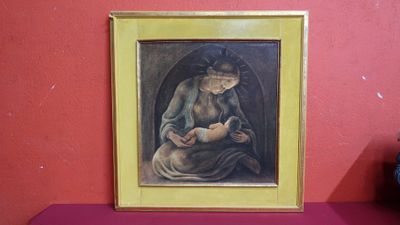un tableau représentant une femme tenant un bébé dans ses bras, posé sur une étagère