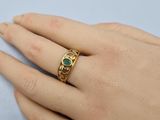 someone wearing a gold ring with a green stone on it