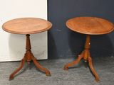 une paire de tables d'appoint anciennes en bois, posées sur des socles, devant un mur noir