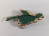 gold and green bird broochle sitting on a white surface