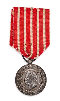 un gros plan d'une médaille sur fond blanc, ornée d'une bande rouge et blanche