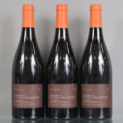 trois bouteilles de vin rouge sont posées sur une table en verre