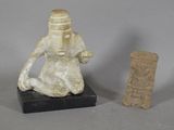 une petite statue représentant un homme assis à côté d'une autre petite statue représentant un homme