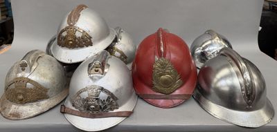 cinq casques posés sur une table : un rouge, un argenté et un doré