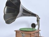 un vieux gramophone avec une plaque verte posée sur un socle en bois