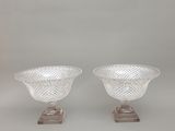 une paire de vases en verre transparent posés sur des socles, sur fond blanc