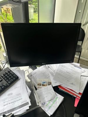 a computer monitor sitting on a desk with papers and a keyboard