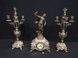 three antique bronze figurines and a clock on a black background