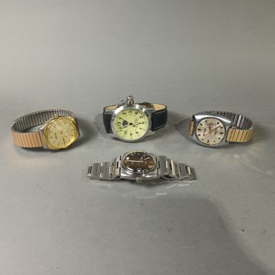 Quatre montres différentes sont posées les unes à côté des autres sur une table.