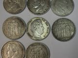 six pièces d'argent de tailles et de formes différentes sur une surface blanche