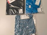three men ' s t - shirts in plastic bags on a table
