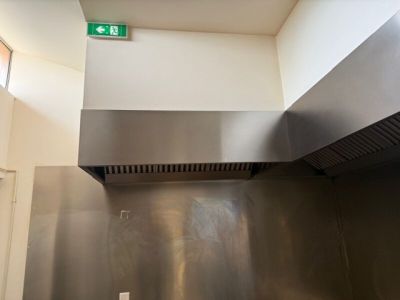 un panneau vert « Sortie de secours » au-dessus d'une cuisinière en acier inoxydable