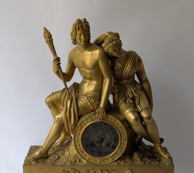 a gold statue of a man and a woman sitting on a clock