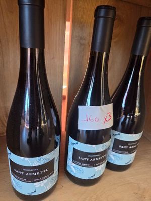 four bottles of wine are lined up on a wooden shelf