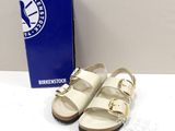 pair of white birkenstos sandals on a white surface next to a blue box