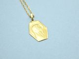 a gold plated necklace with an image of jesus on it