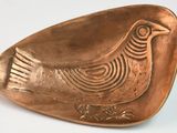 a small copper plate with a bird on it