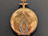 an image of a gold pocket watch on a black surface