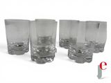 six clear glasses are lined up in a row on a white surface