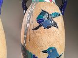 two vases with birds painted on them sitting on a table