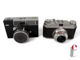 two cameras sitting next to each other on a white surface
